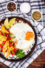 Grilled chicken meat with rice and fried egg on wooden table
