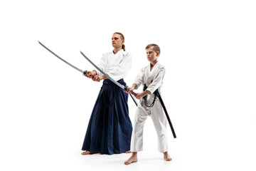 Man and teen boy fighting at Aikido training in martial arts school. Healthy lifestyle and sports concept. Fightrers in white kimono on white background. Karate men with concentrated faces in uniform.