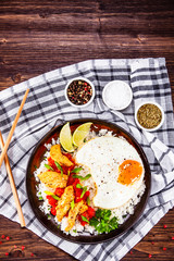 Grilled chicken meat with rice and fried egg on wooden table