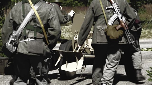 Soldiers move a anti tank gun along a street