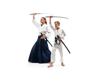 Man and teen boy fighting at Aikido training in martial arts school. Healthy lifestyle and sports concept. Fightrers in white kimono on white background. Karate men with concentrated faces in uniform.