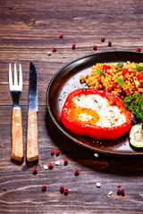 Fried egg, groats and vegetables on wooden table