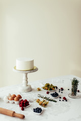 homemade white ckae covered with icing, ingredients for creative decoration on the table