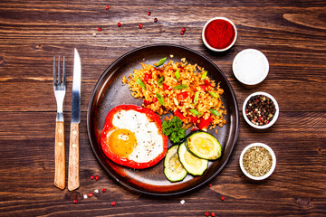 Fried egg, groats and vegetables on wooden table