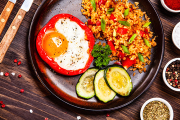 Fried egg, groats and vegetables on wooden table