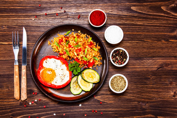 Fried egg, groats and vegetables on wooden table