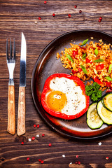 Fried egg, groats and vegetables on wooden table