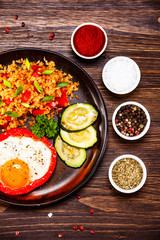 Fried egg, groats and vegetables on wooden table