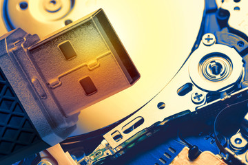 Toned image of USB memory stick against hard disk drive plate background. Technology concept.