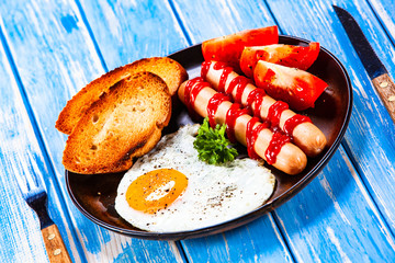 English breakfast - fried egg, sausages, toasts and vegetables