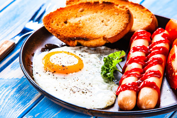 English breakfast - fried egg, sausages, toasts and vegetables