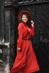Outdoor portrait of young beautiful happy smiling fashionable lady wearing orange hat, snakeskin...