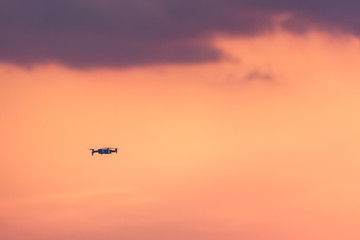 Drone with remote control. Dark silhouette against colorful sunset. Soft focus. Toned image