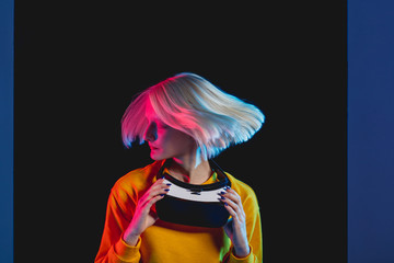 girl with flying fair hair holding VR glasses, close up photo. isolated black background , hair care