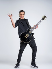 Fototapeta premium Fifteen years old guitarist with a black electric guitar. Teenage musician holds guitar