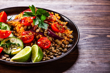 Groats with lentils and vegetables on wooden table
