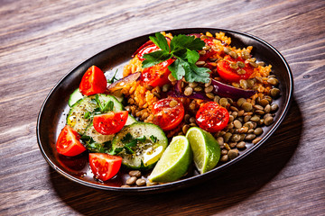 Groats with lentils and vegetables on wooden table