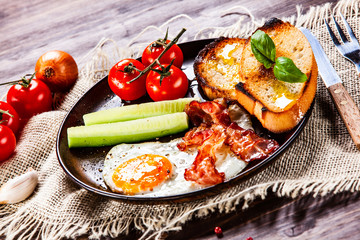 Breakfast - fried egg ,toasts,bacon, and vegetables