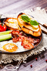 Breakfast - fried egg ,toasts,bacon, and vegetables