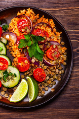 Groats with lentils and vegetables on wooden table