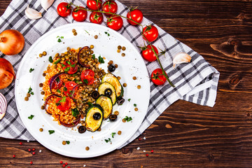 Groats with lentils and vegetables on wooden table