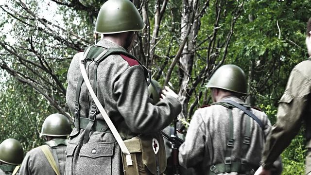 Soldier makes his gun redy while a group is passing him