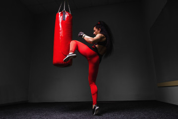Kickboxing young woman punching kicking the bag