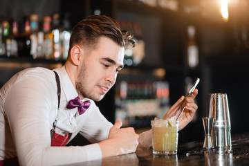 Professional bartender preparing a refreshing cocktail decorating it with a slice of lime.