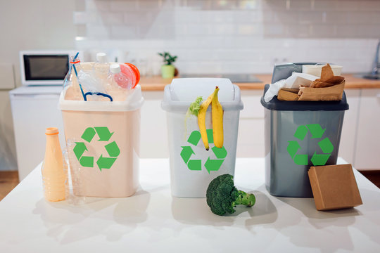 Waste sorting at home. Protect the environment. Colorful garbage bins with recycling icon full of plastic, food, paper on the table close-up