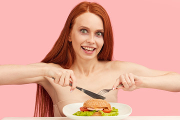 Diet failure of emaciated skinny redhead woman feeling excitement and joy when is going to eat unhealthy food hamburger.