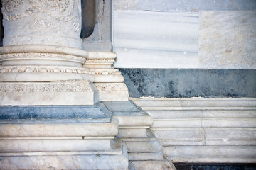 Base of the marble columns with white stone frame of a romanesque Italian church