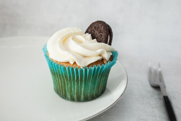cupcakes with white cheese cream decorated with cookies on a white plate