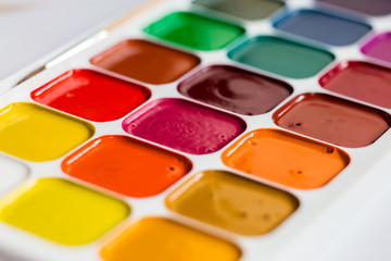 Multi-colored bright Watercolor paints on a table close up