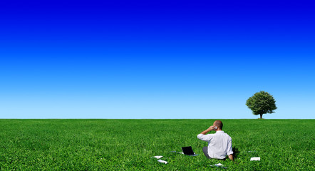Businessman sitting on green field