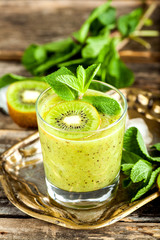 Glass of kiwi smoothie with fresh fruits on a wooden table