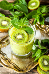 Glass of kiwi smoothie with fresh fruits on a wooden table