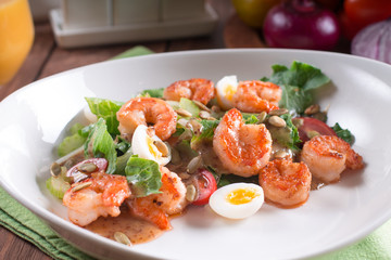 Healthy salad. Recipe for fresh seafood. Grilled shrimp, fresh vegetable salad and egg. Shrimp on the grill. Health food. Wooden background