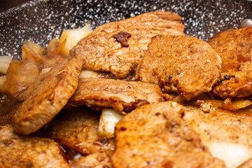 Cooking fryed meat on the pan with onion close up