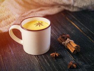 Turmeric with milk, cinnamon and anise on a wooden table. Healthy home drink
