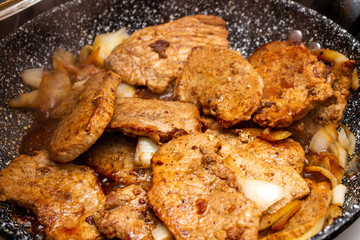 Cooking fryed meat on the pan with onion close up