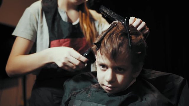 Close-up of a hairdresser doing a hair-dressing machine for a boy. Haircut of a children's hair trimmer and comb at the hairdresser.