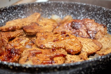 Cooking fryed meat on the pan with onion close up