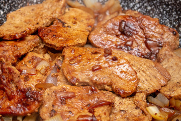 Cooking fryed meat on the pan with onion close up