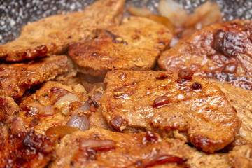 Cooking fryed meat on the pan with onion close up