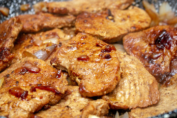 Cooking fryed meat on the pan with onion close up