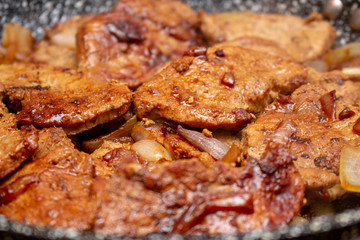 Cooking fryed meat on the pan with onion close up