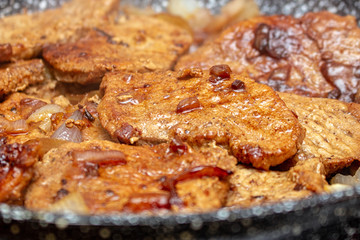 Cooking fryed meat on the pan with onion close up