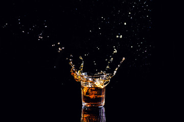 whiskey with splash on black background, brandy in a glass