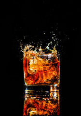 whiskey with splash on black background, brandy in a glass