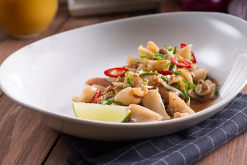 The traditional Asian dish is grilled squid with spicy paprika and tomatoes. wooden background